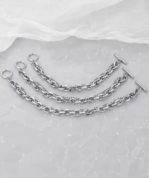 Set of silver chain necklaces on a textured gray surface
