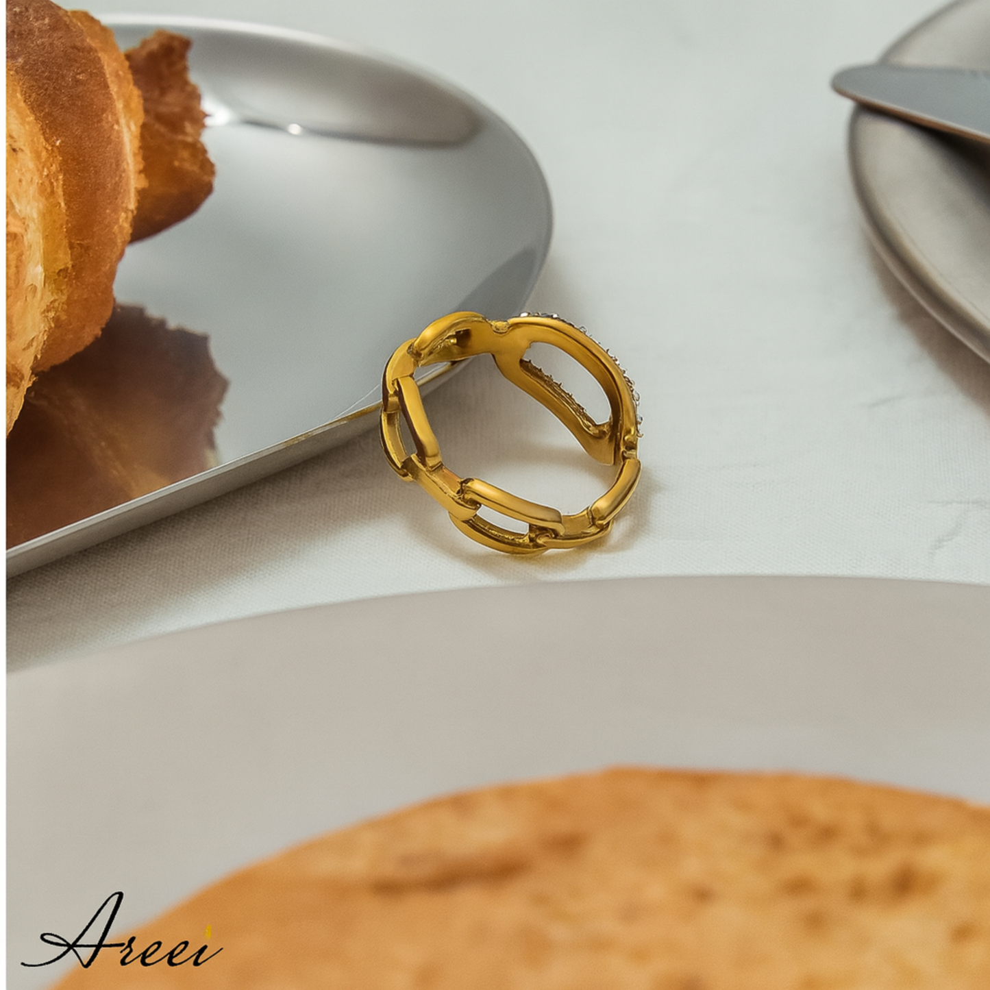 Gold ring on a white surface with pastries in the background