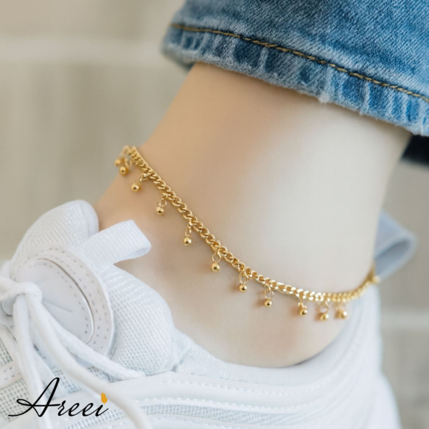 Gold anklet on a person's ankle with a blurred background