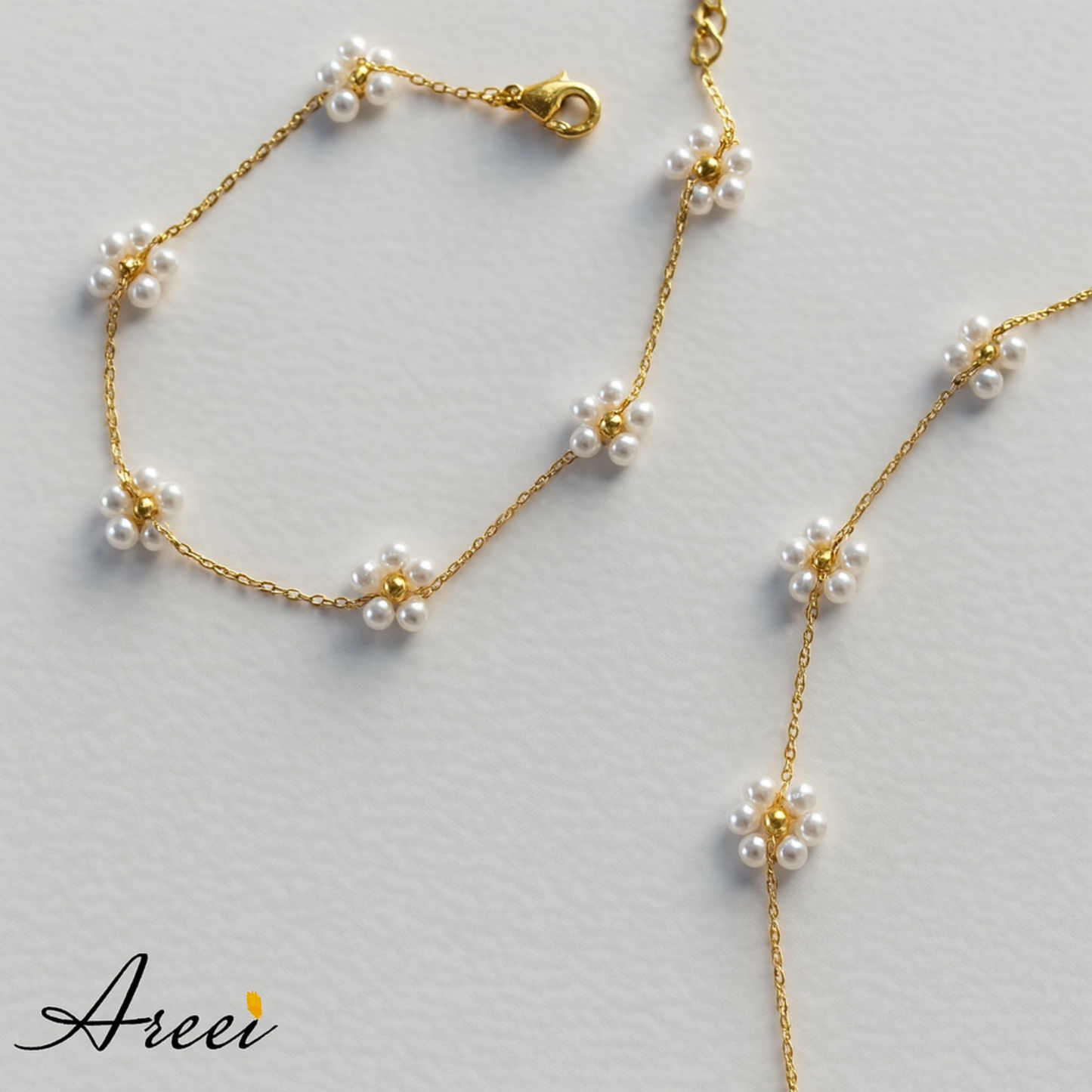 Gold necklace with pearl flowers on a light gray background, featuring the brand 'Areei'.