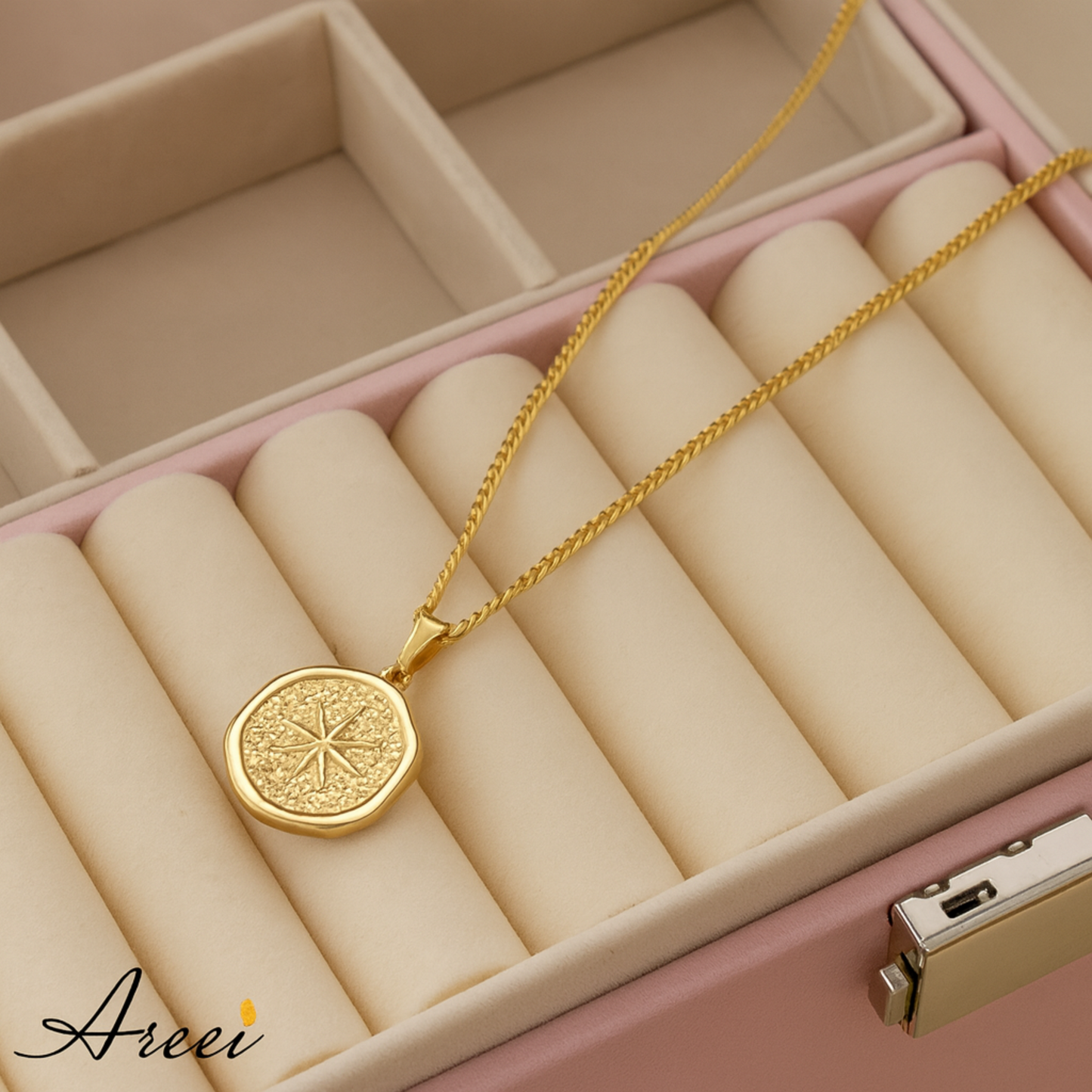 Gold necklace with a circular pendant on beige jewelry rolls in a pink jewelry box.