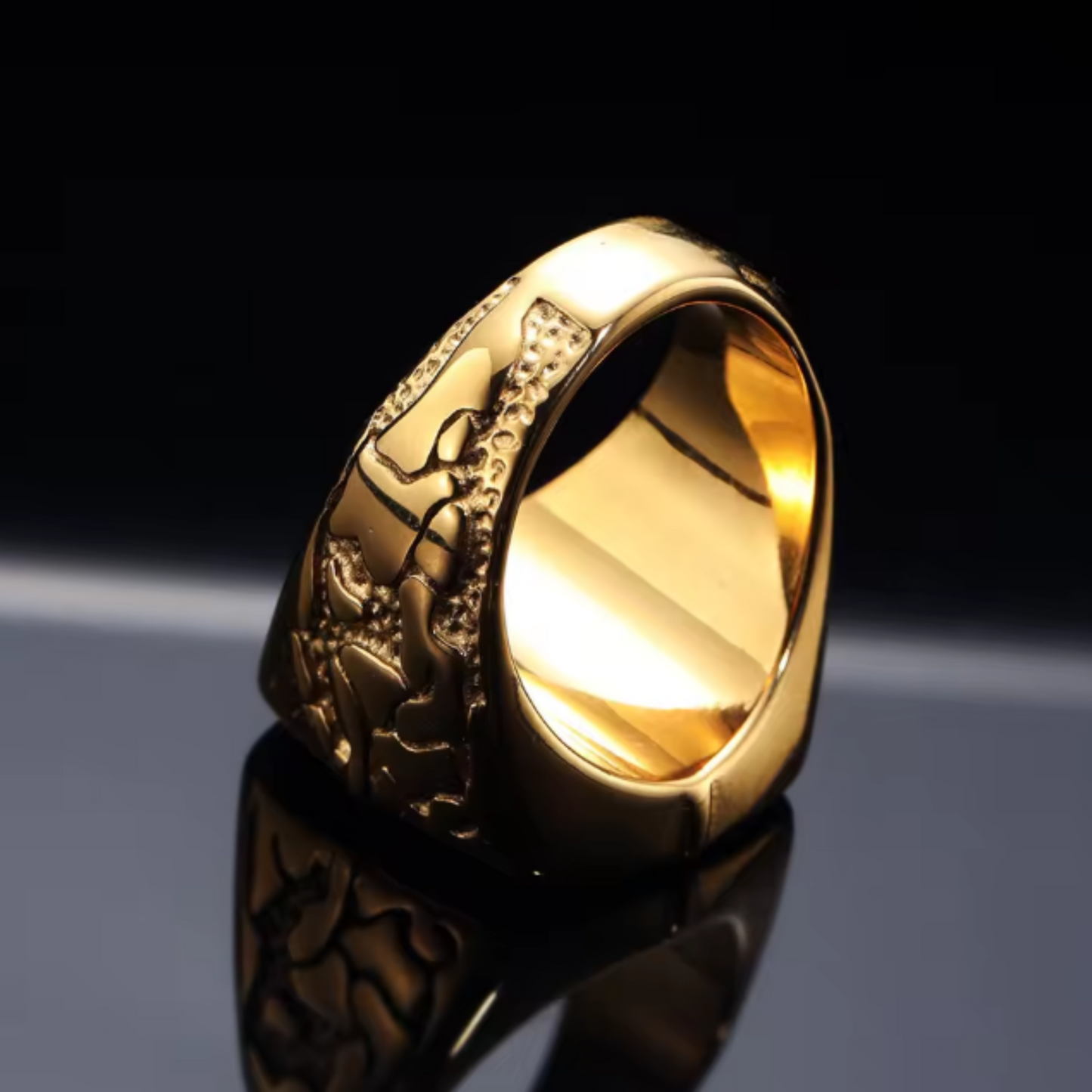 Gold ring with intricate design on a reflective surface