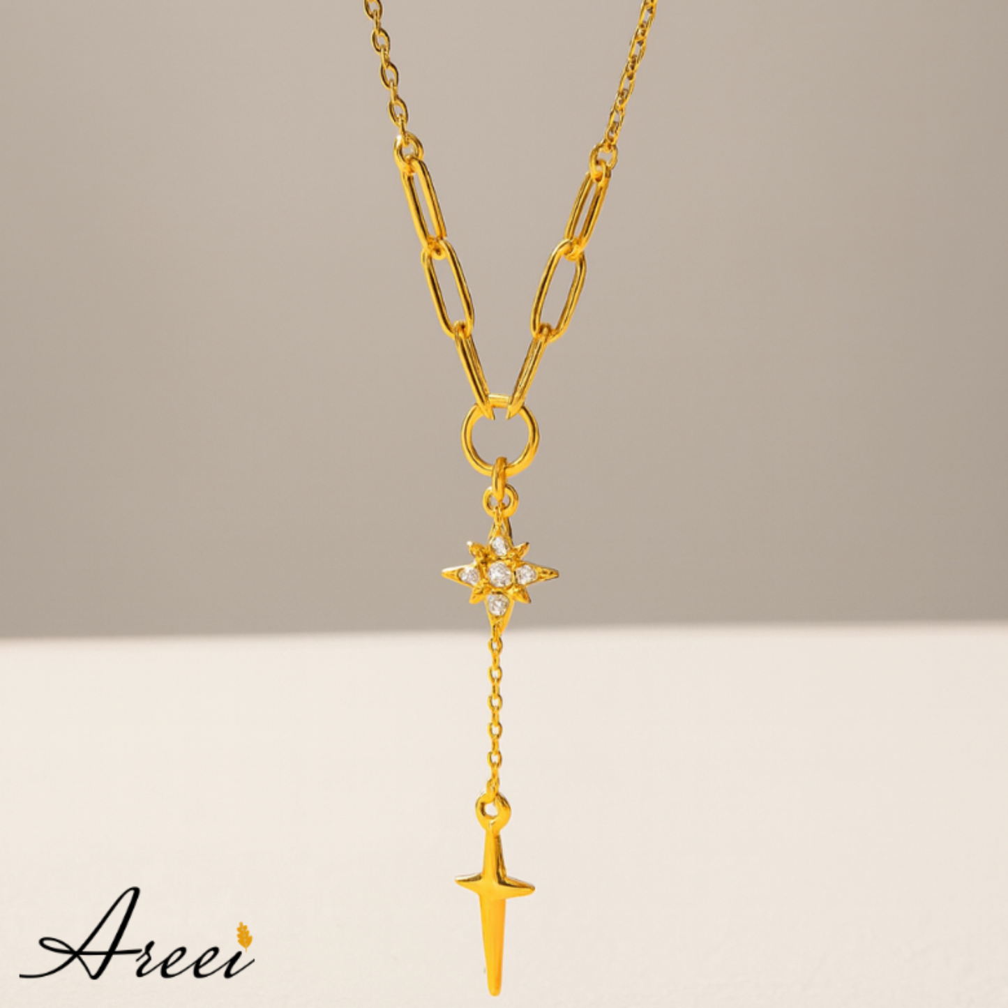 Gold necklace with star and arrow pendant on a neutral background, featuring the brand 'Areei'.