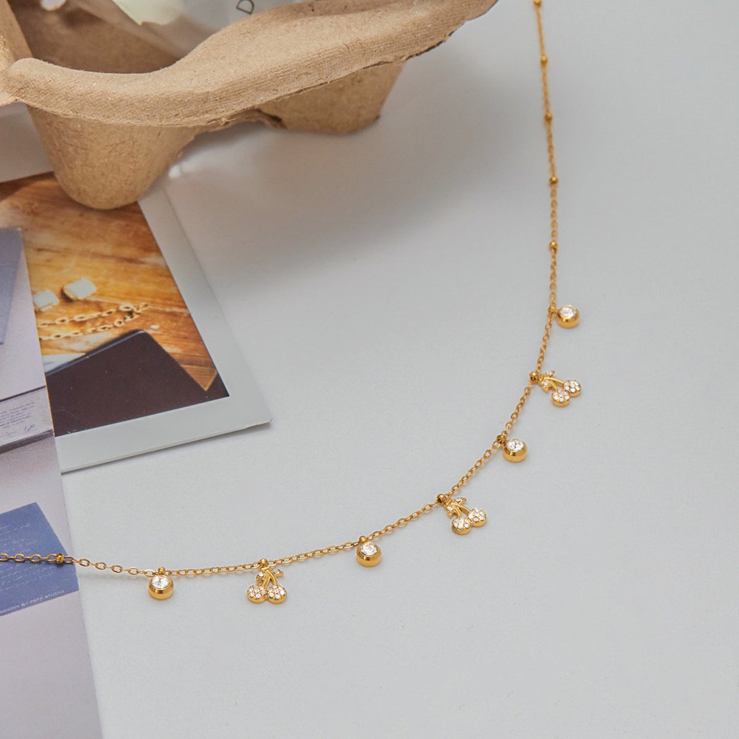 Gold necklace with small pendants on a light gray surface