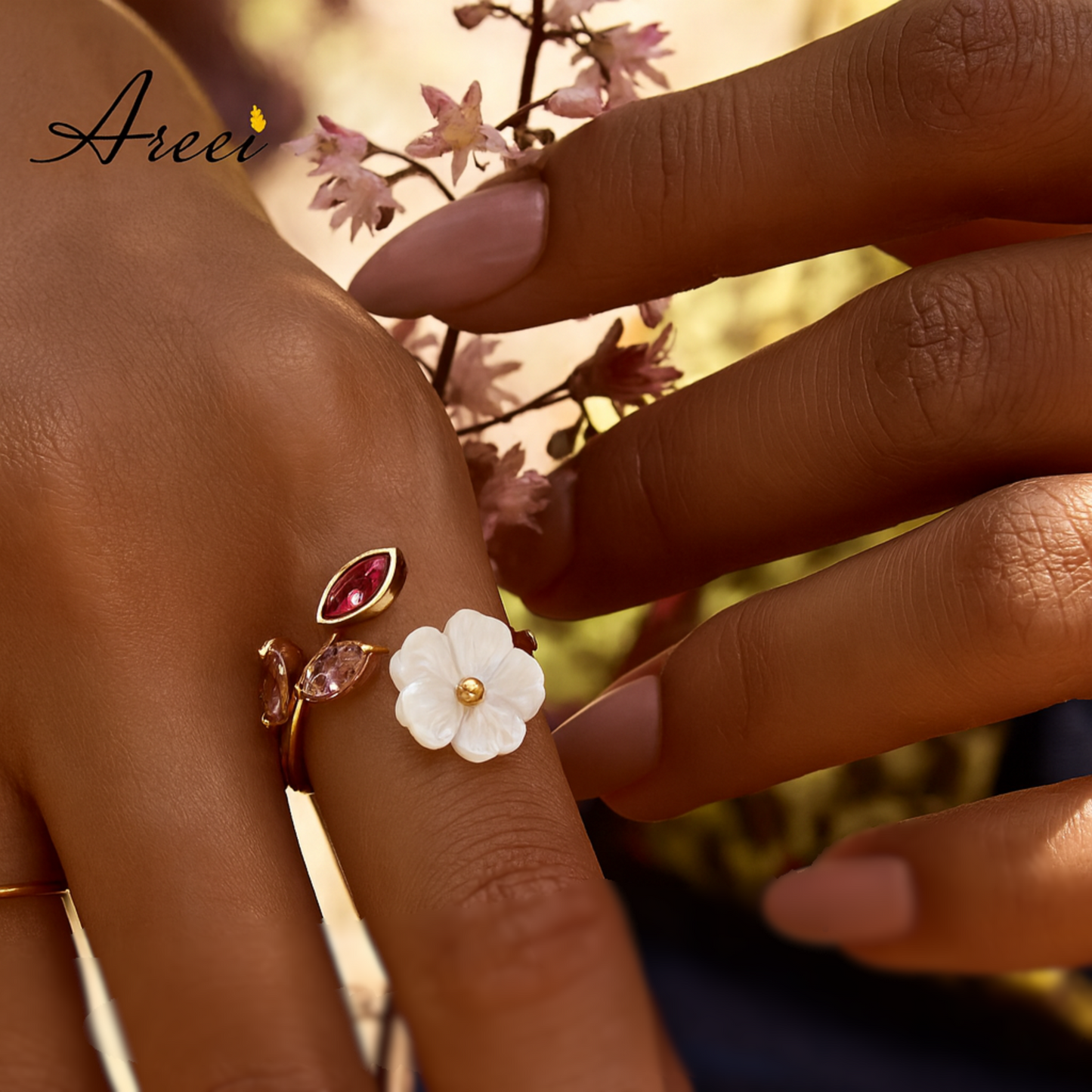 Close-up of a hand wearing a decorative ring with floral design against a blurred natural background