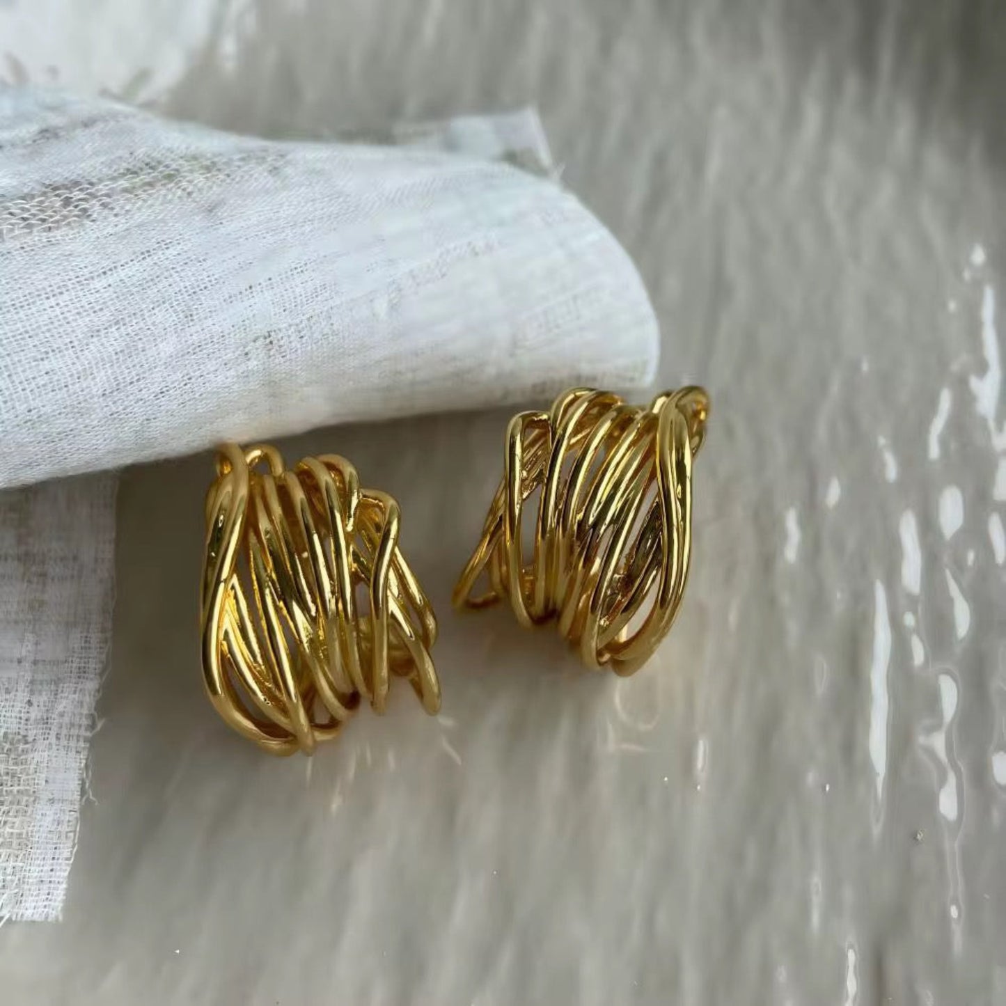 Pair of gold spiral earrings on a textured white surface