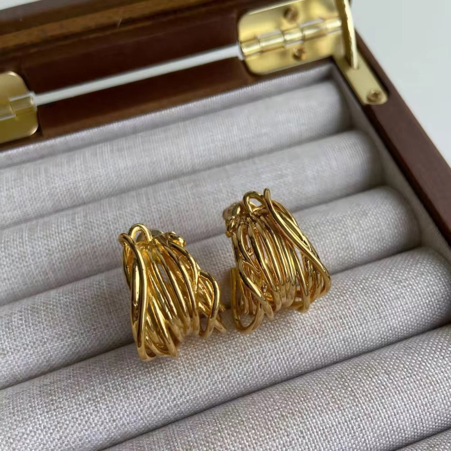 Gold hoop earrings in a jewelry box on a white background