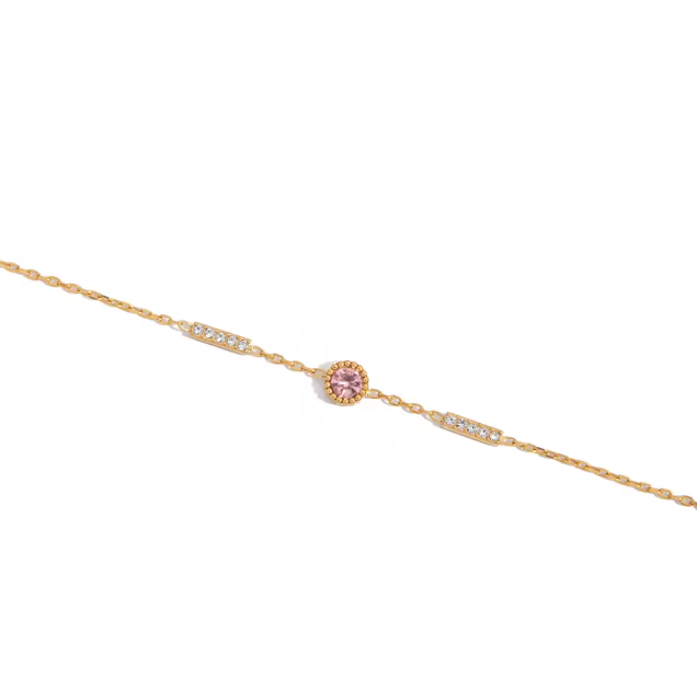 Gold bracelet with a pink gemstone on a white background