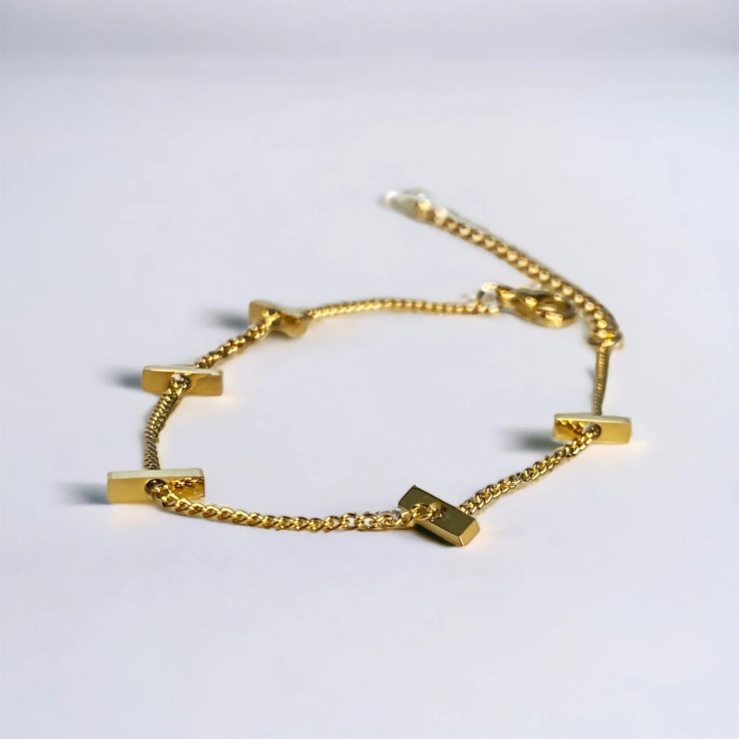 Close up of Thin minimalist gold bracelet with small bars on white surface