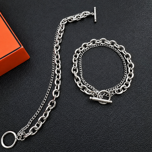 Silver chain belt and bracelet set on a dark surface with an orange box.