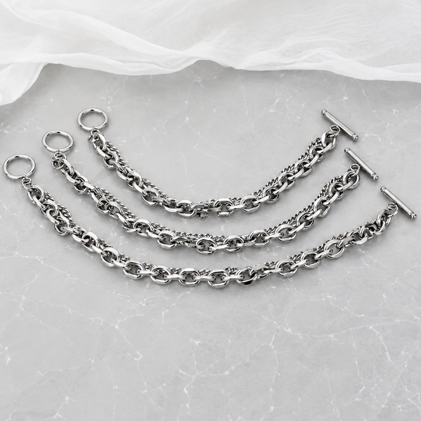 Set of silver chains with clasps on a textured gray surface