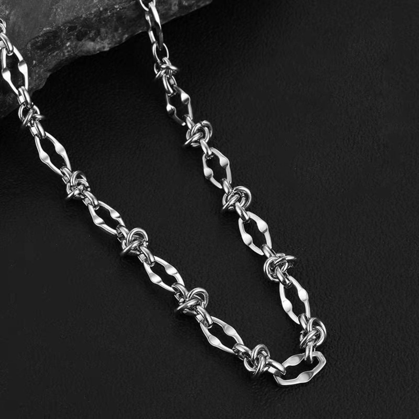 Silver chain necklace on a dark stone surface