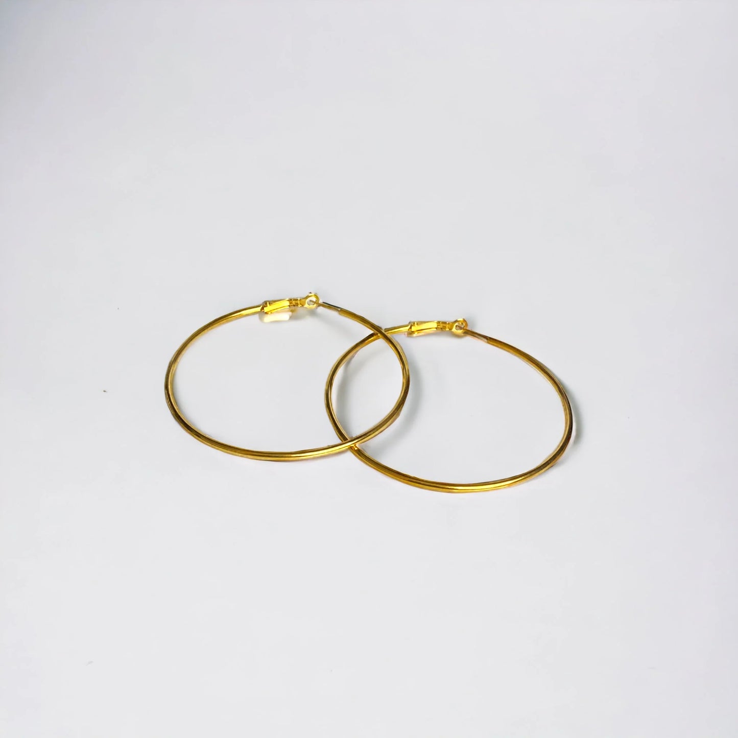 Large gold hoop earrings overlapped on white surface