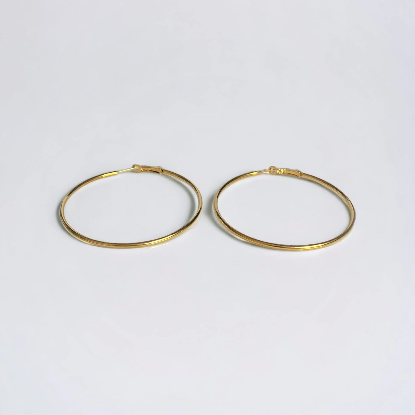 Large Gold hoop earrings on white surface