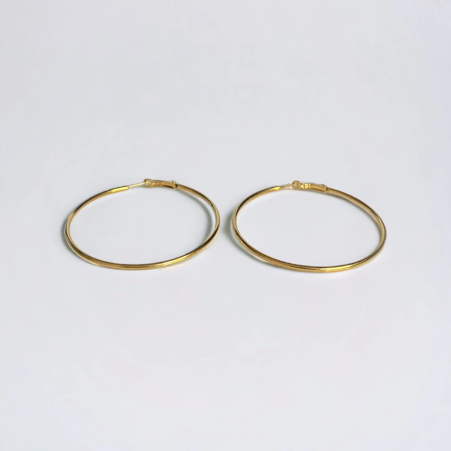 Large Gold hoop earrings on white surface