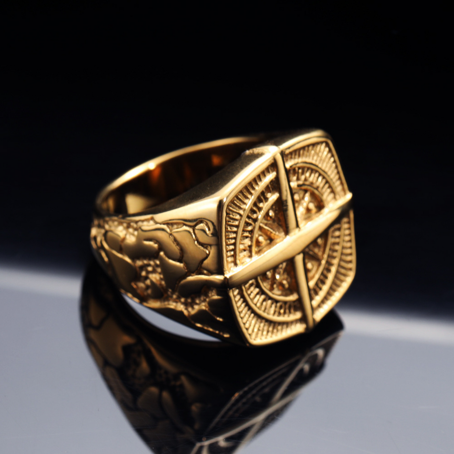 Gold ring with intricate design on a reflective surface