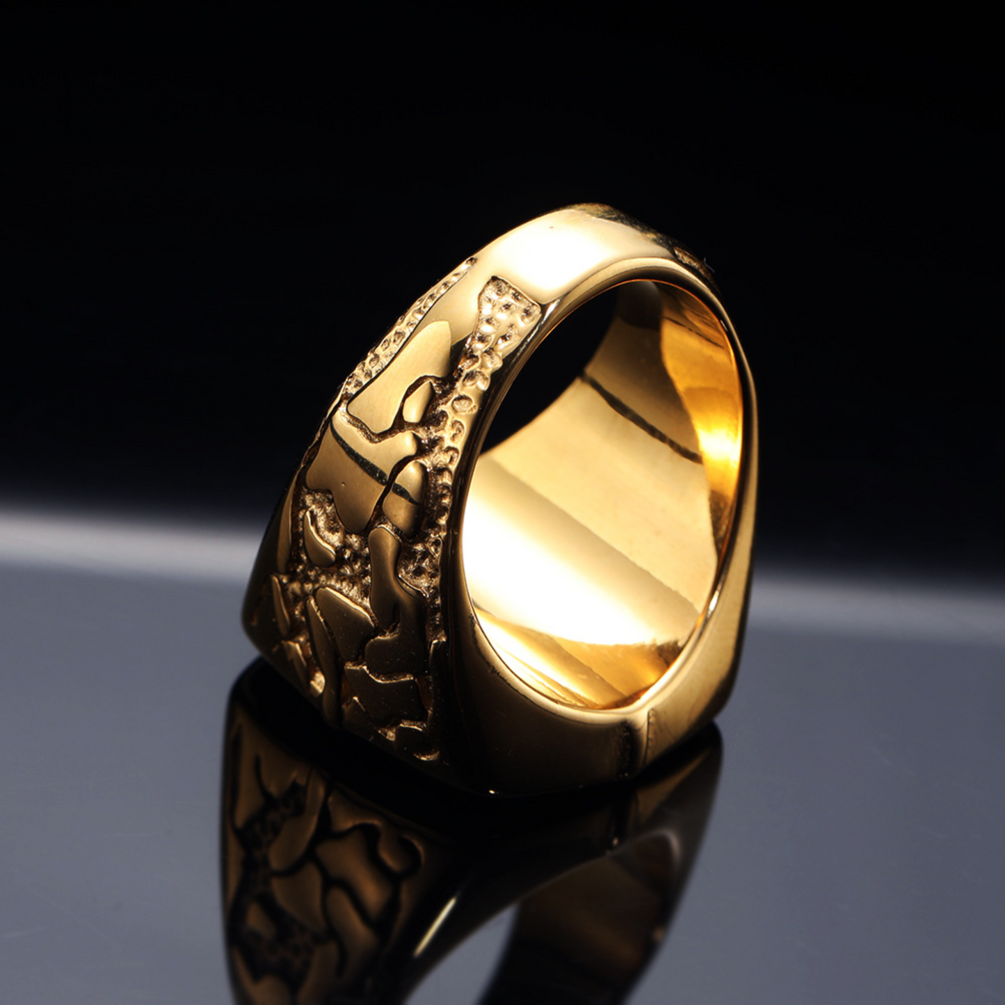 Gold ring with intricate design on a reflective surface