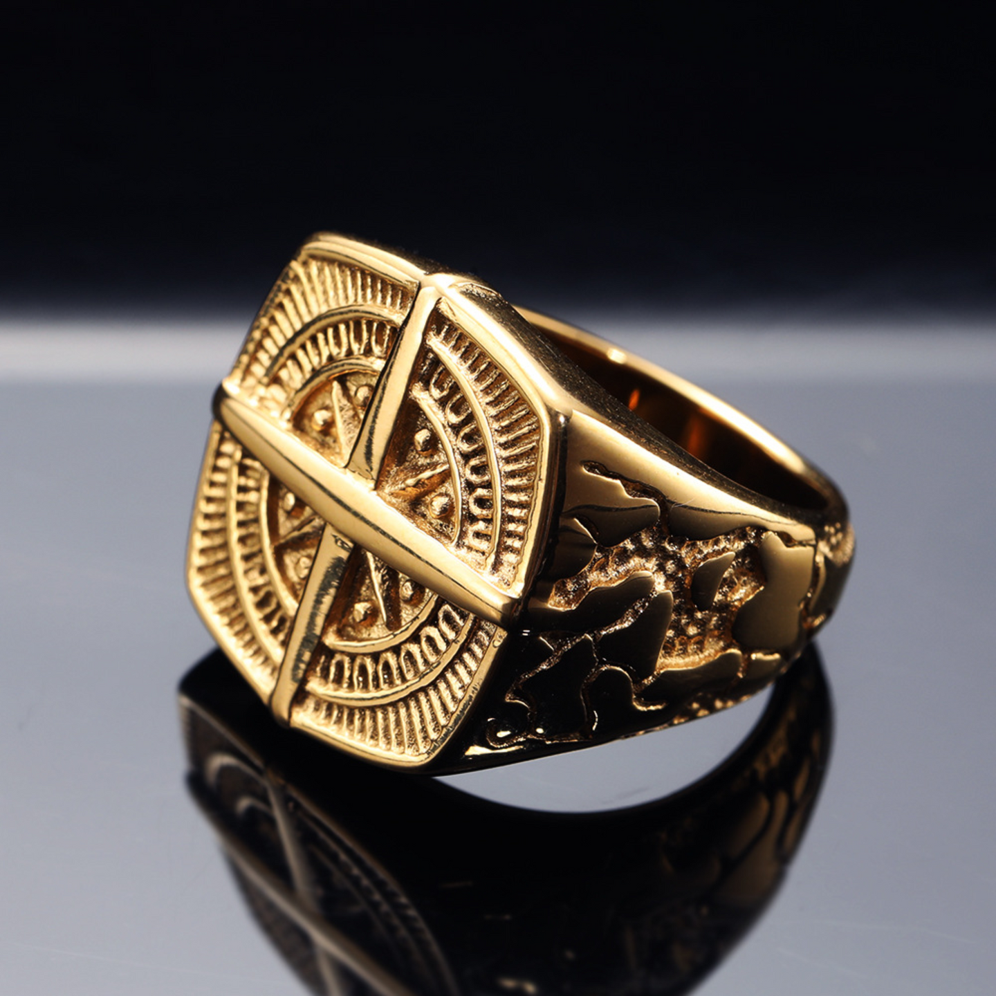 Gold ring with intricate design on a reflective surface