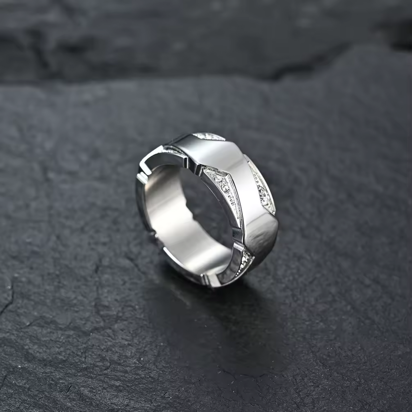 Silver ring with geometric design on a dark stone surface