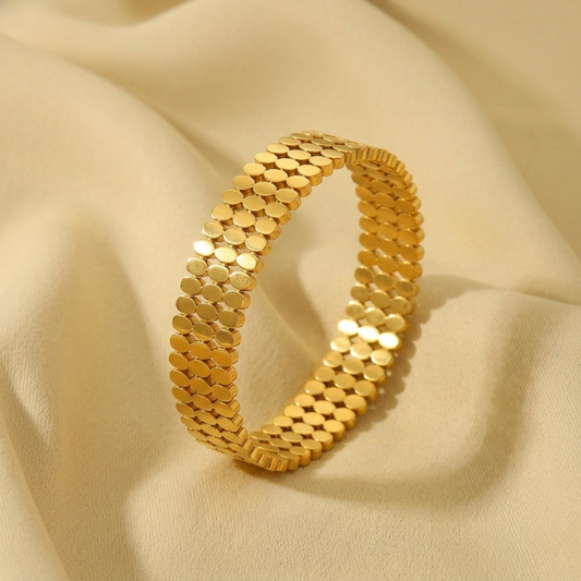 Gold bracelet on a beige fabric background