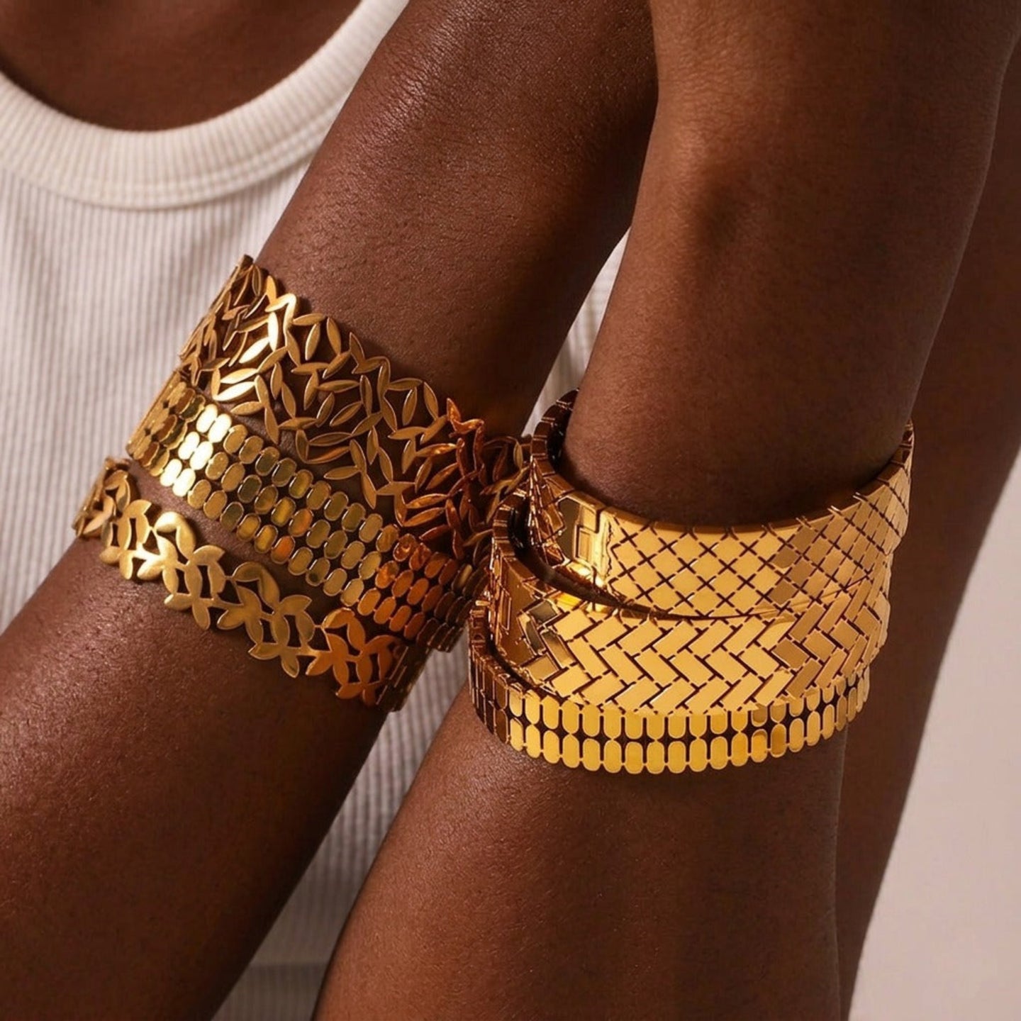 Gold arm cuffs on a person's arms with a neutral background