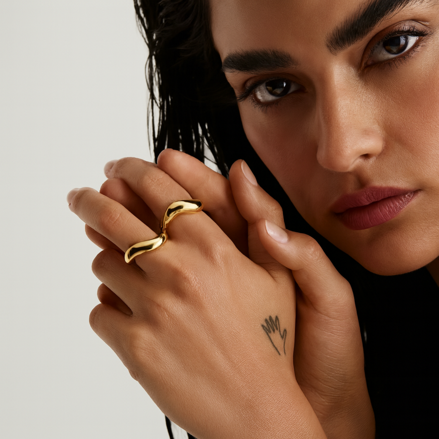Close-up of a woman's hand wearing a gold ring with a neutral background