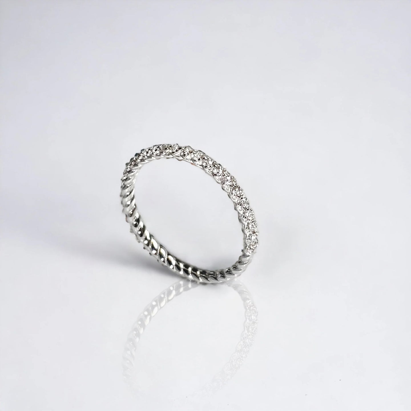 Silver minimalist ring with cubic zirconia mini diamonds on white surface