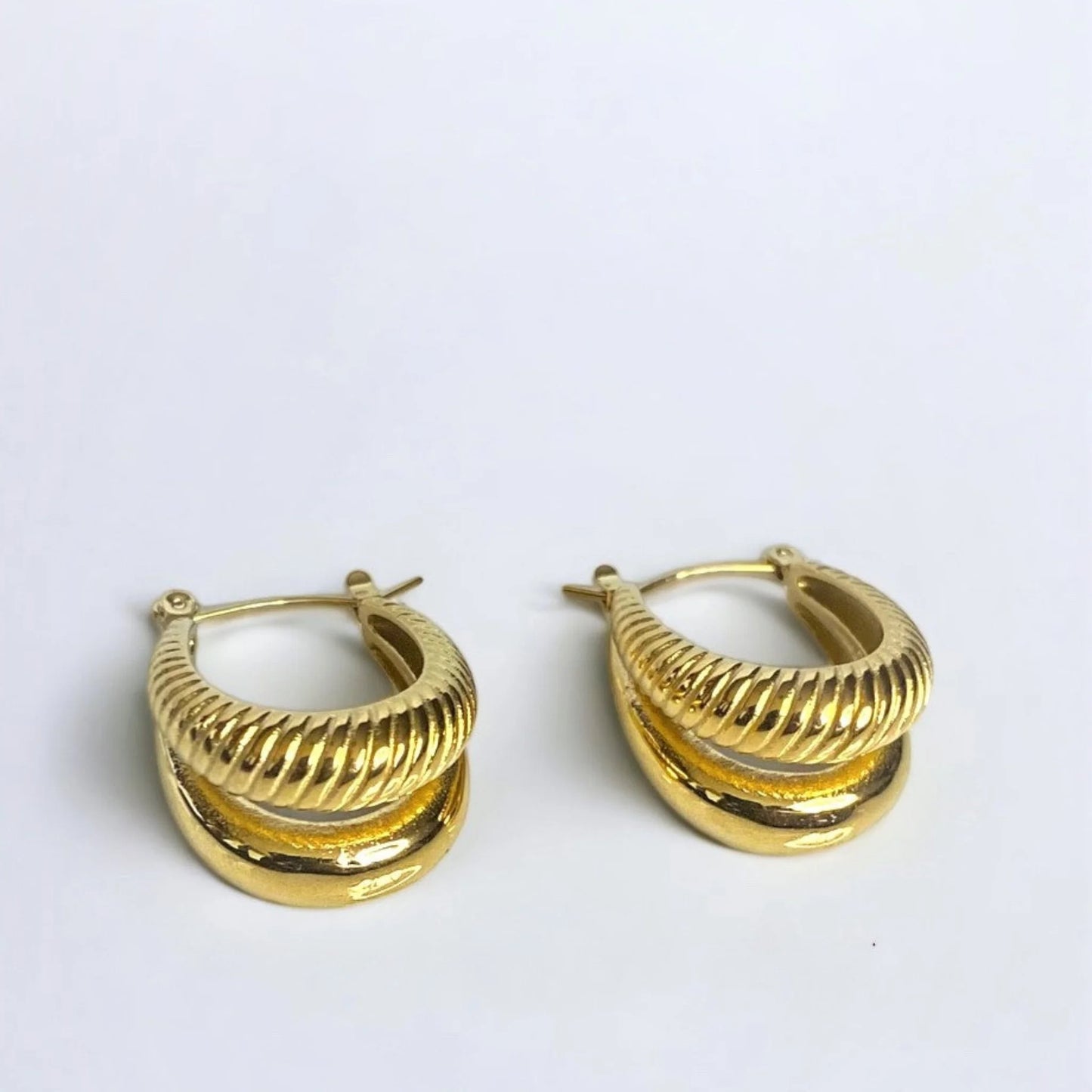 Chunky gold earrings with two texture on white surface