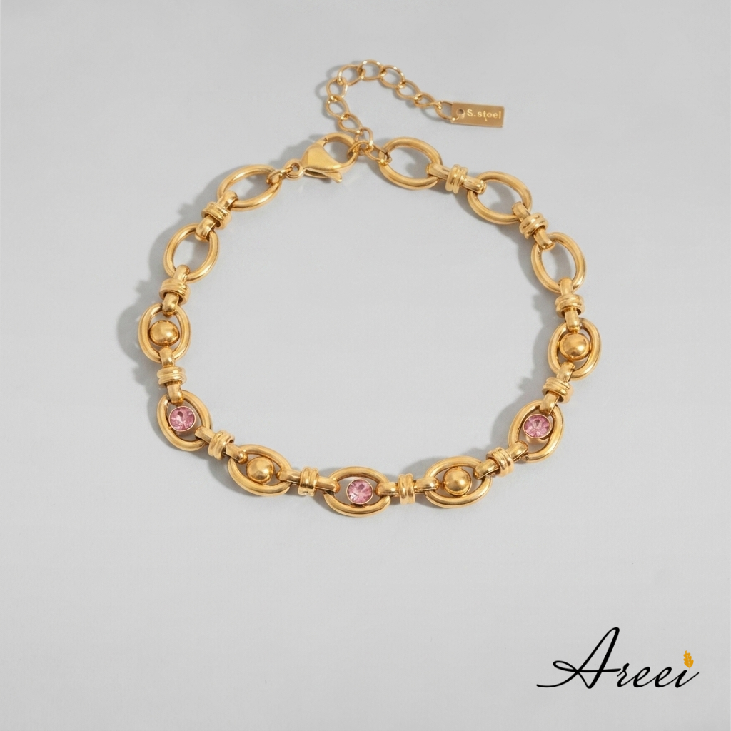 Gold bracelet with pink stones on a gray background, featuring the brand 'Areei'.