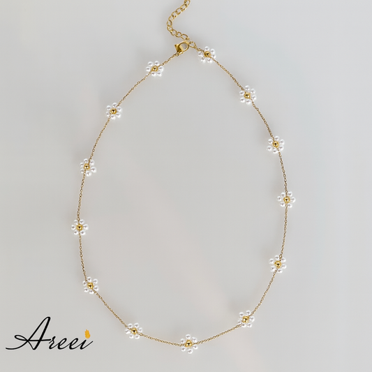Delicate gold necklace with floral pendants on a light gray background, featuring the brand 'Areev'.