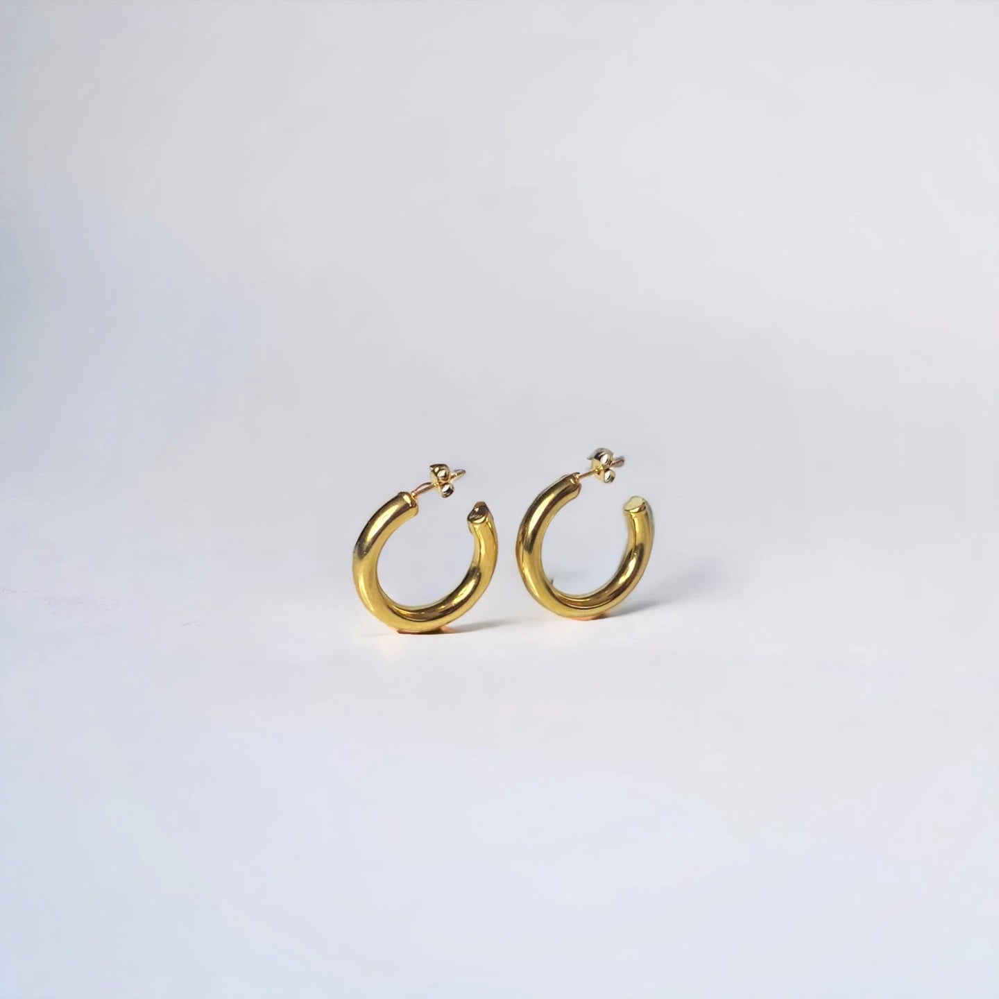 standing Half hoop gold earring on white surface