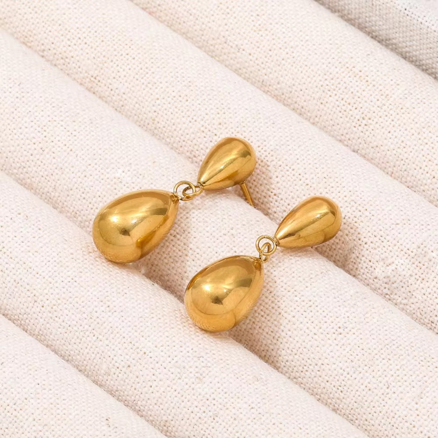Pair of gold earrings on a textured beige surface