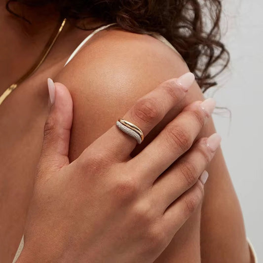 Close-up of a hand wearing a gold ring with a diamond, holding a shoulder.