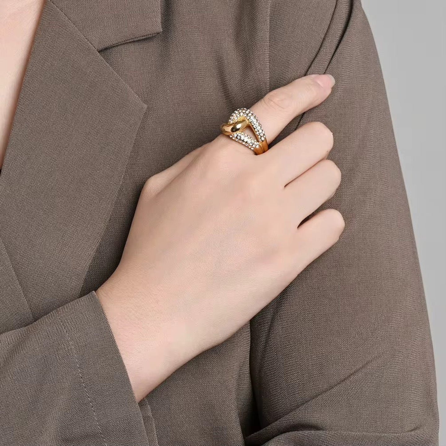Hand wearing a gold ring with a brown background