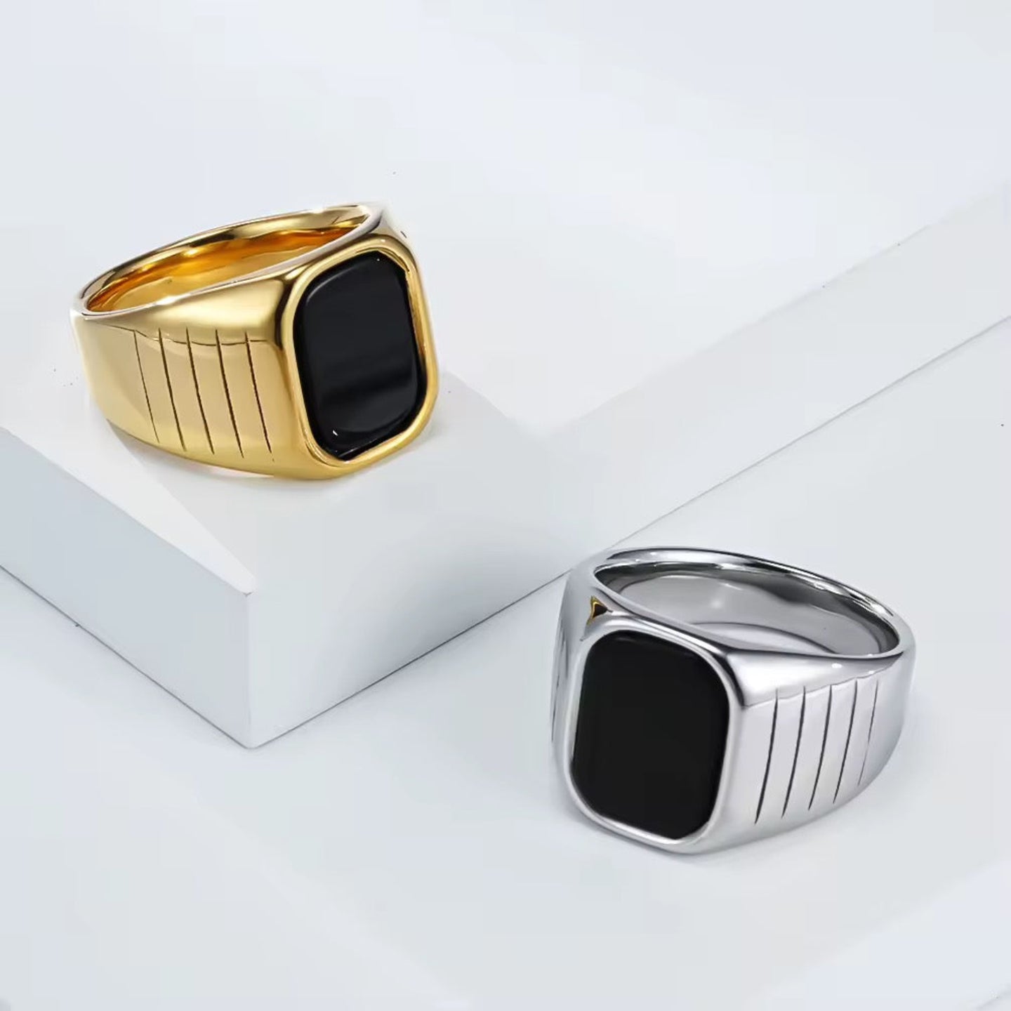 Two rings, one gold and one silver, on a white surface.