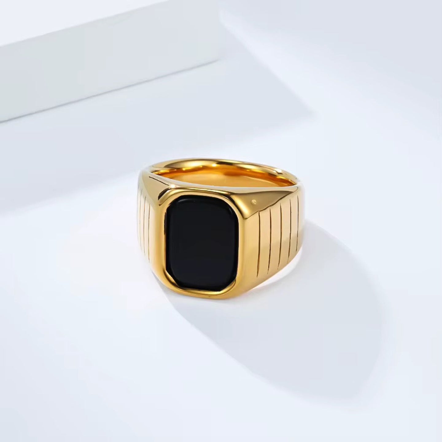 Gold ring with a black stone on a white surface