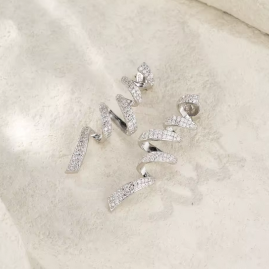 Silver spiral earrings with clear stones on a light beige background