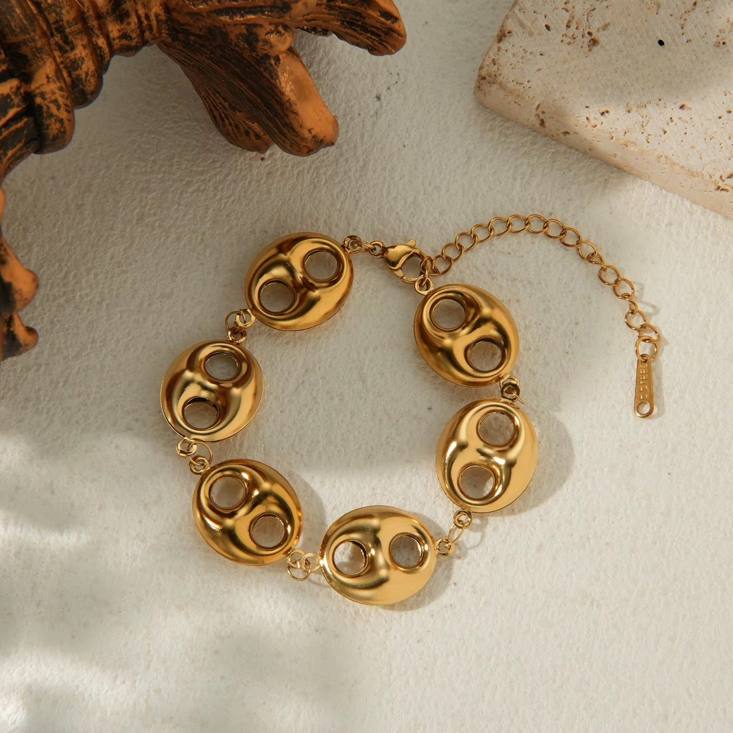 Gold bracelet on a textured beige surface with a rustic background