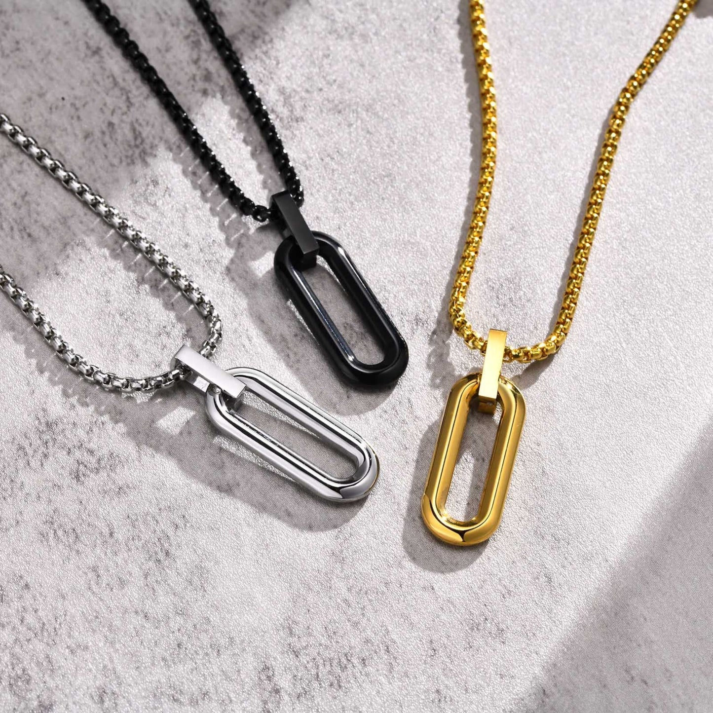 Three necklaces with different chain designs on a textured surface