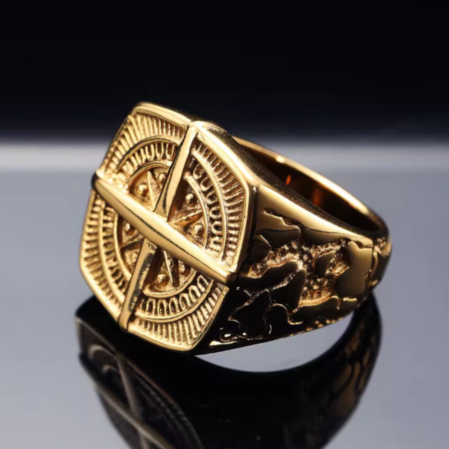 Gold ring with intricate design on a reflective surface