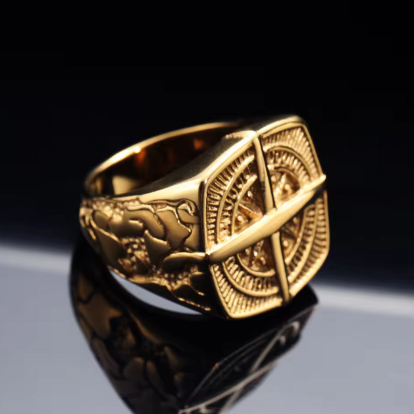 Gold ring with intricate design on a reflective surface