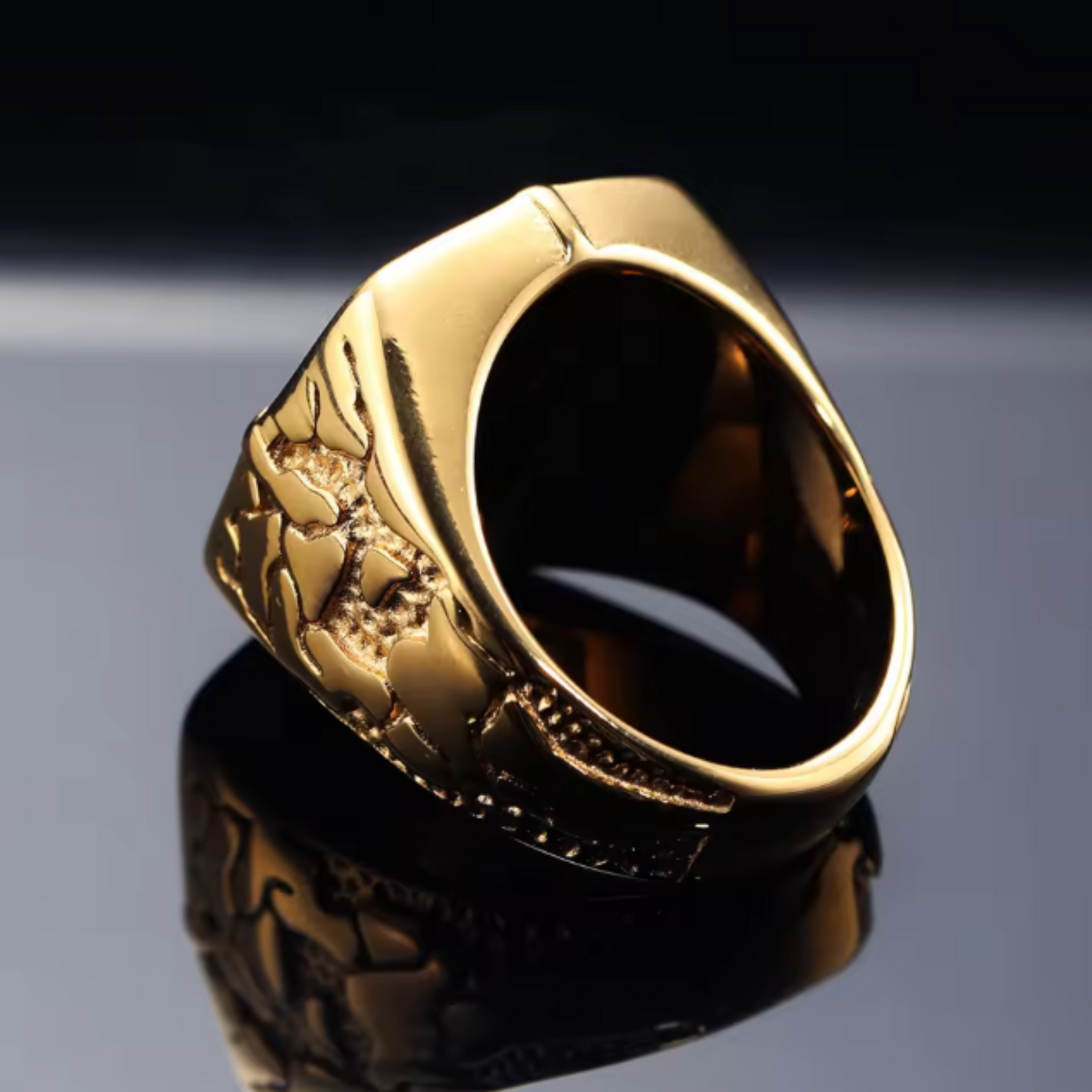 Gold ring with intricate design on a reflective surface