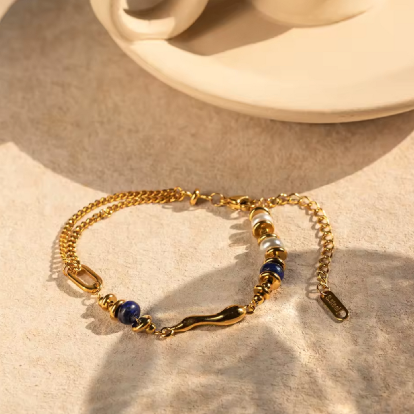 Gold bracelet with blue beads on a beige surface