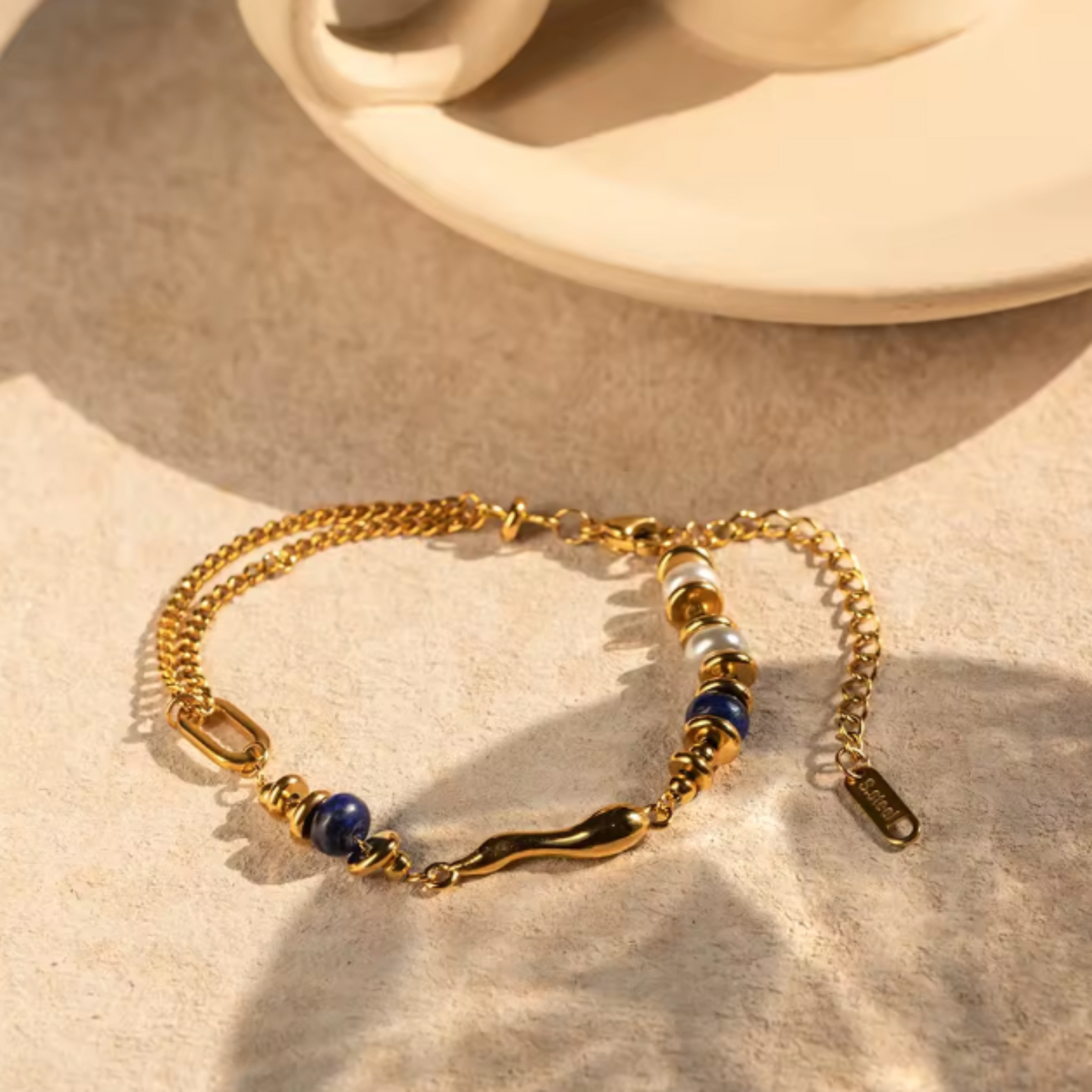 Gold bracelet with blue beads on a beige surface