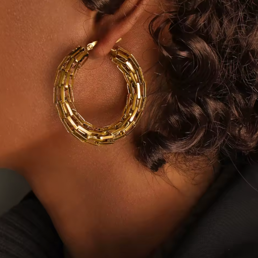 Close-up of a person wearing gold hoop earrings with a blurred background