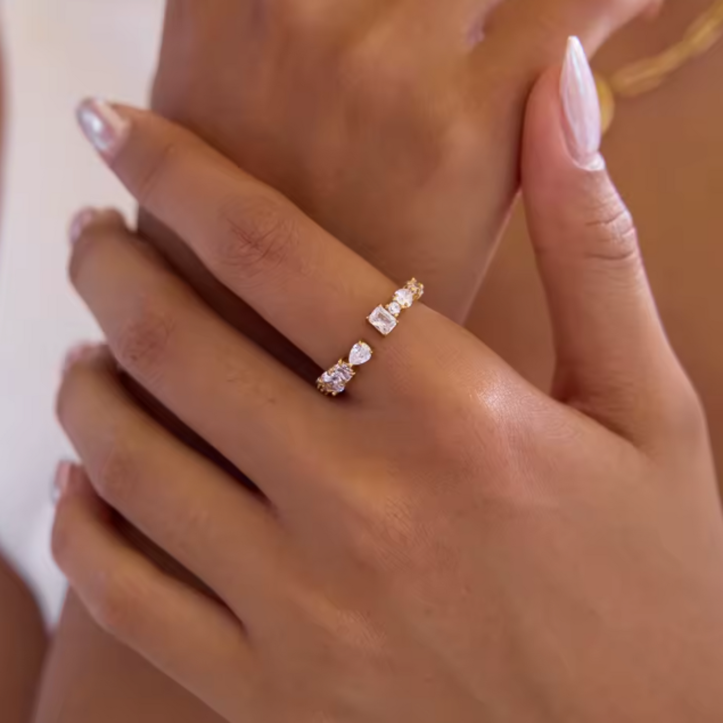 Close-up of a hand wearing a diamond ring on a neutral background