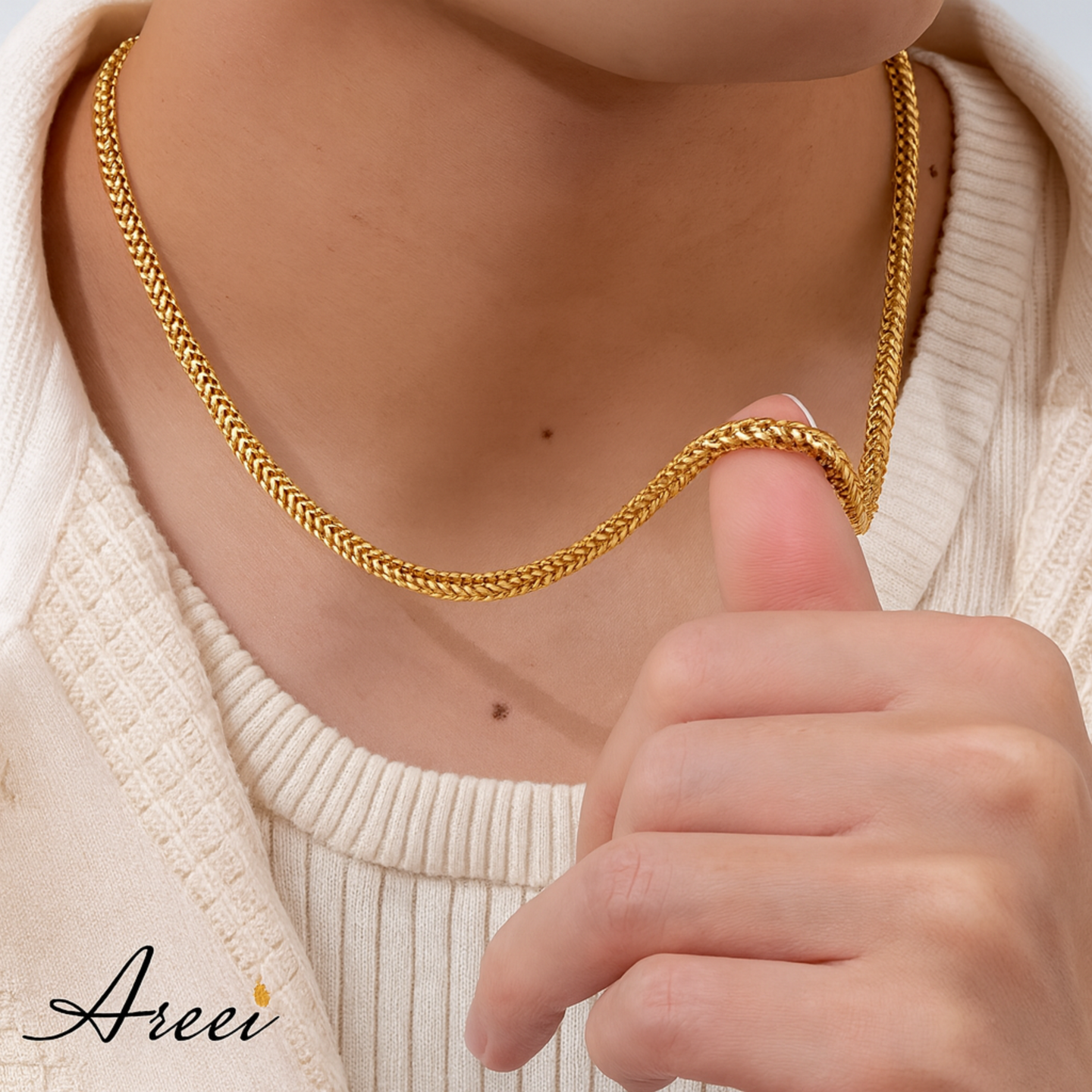 Gold chain necklace being held by a hand, with 'Areei' brand visible.