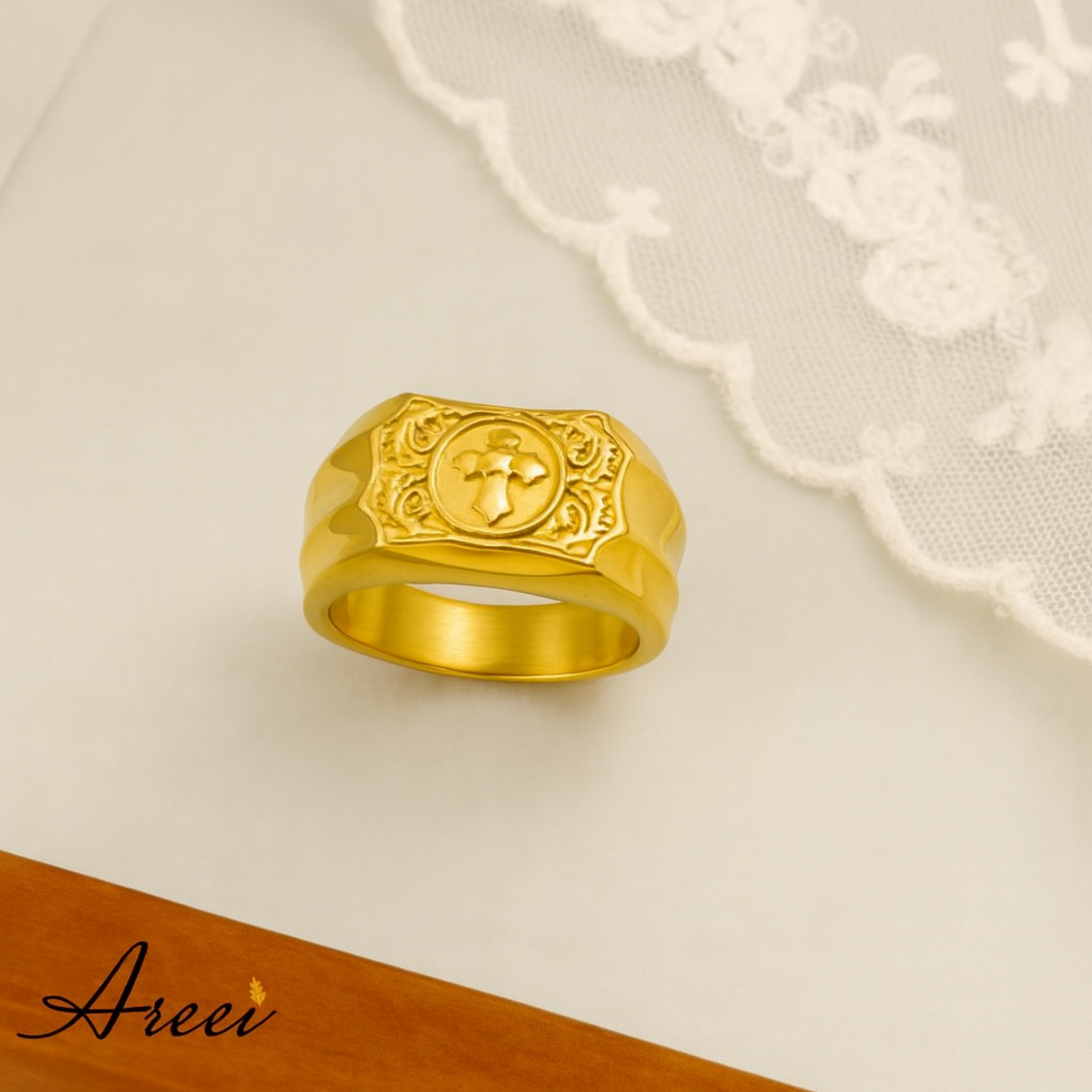 Gold ring with intricate design on a beige background